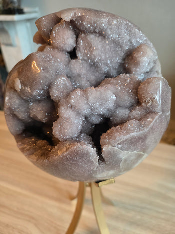 Angled view of 59cm circumference pink amethyst geode sphere on rotating stand