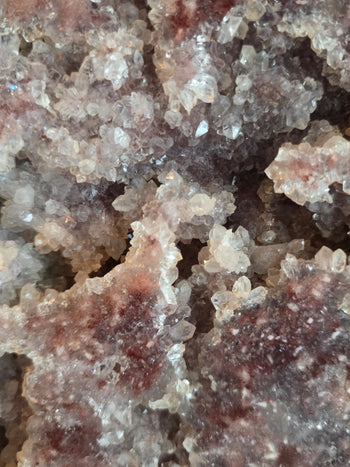 Close-up of sparkling clear and frosted quartz crystals on pink amethyst