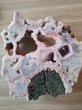 Polished back of 13kg pink amethyst geode showing over a dozen crystal-lined geode pockets