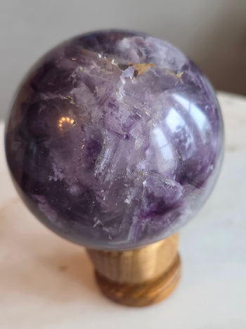 Purple and yellow fluorite sphere 812g, 8cm, on wooden stand – front view