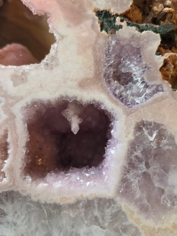 Small crystal suspended inside a lavender amethyst geode pocket