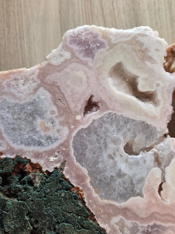 Polished lavender and frosted white crystal pockets in a pink amethyst geode
