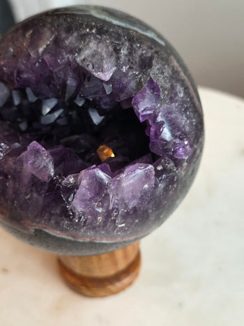 Angled view of amethyst geode crystal ball with open purple crystal cave