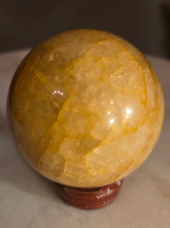 Golden healer quartz sphere with honey-gold iron veils glowing in the light