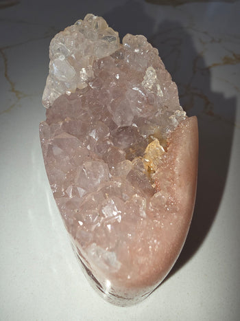 Pink amethyst crystal points inside a natural cut-base geode, view from above