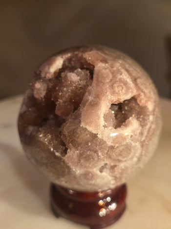 Pink amethyst sphere druzy cavity with blush-pink crystal clusters and agate eyes