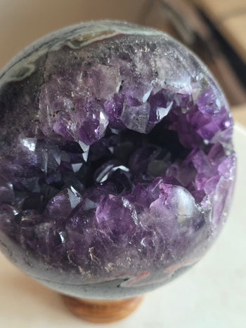 Deep violet amethyst points inside the cavity of a polished geode sphere