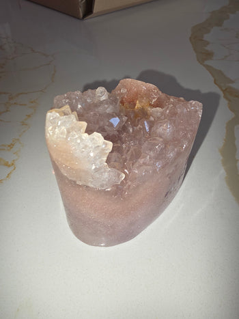 Pink amethyst geode with a crest of clear quartz crystals along the rim
