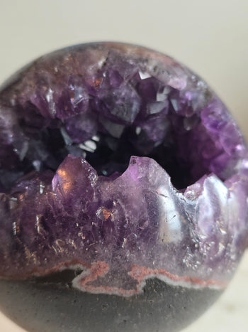 Close-up of amethyst crystals and pink agate band on a Brazilian geode sphere