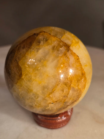 Amber and caramel iron veil inside a golden healer quartz sphere from Brazil