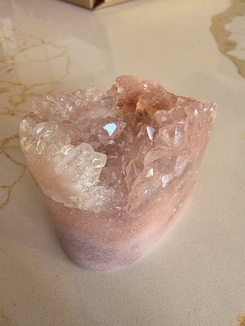 Close-up of blush pink amethyst points and clear quartz in a cut-base geode