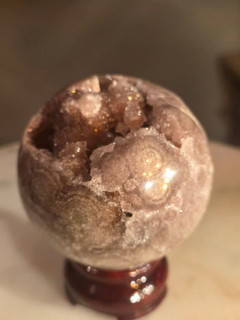 Polished back of pink amethyst sphere showing natural agate banding