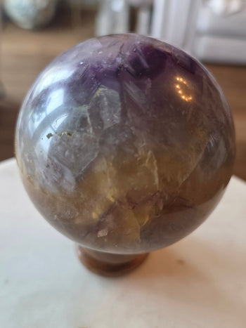 Honey-yellow and amber side of a purple and yellow fluorite sphere