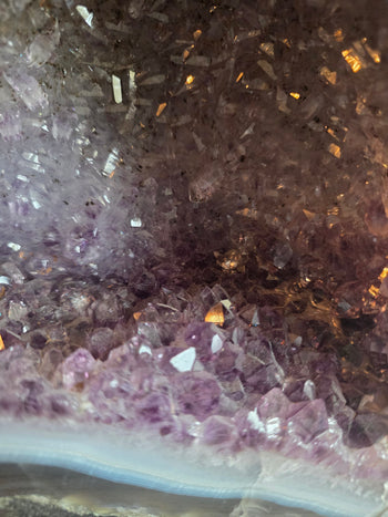 Deep purple amethyst points and blue-grey agate band at the base of a cathedral geode