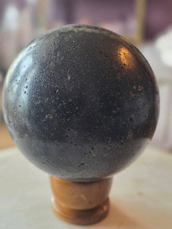Back of amethyst geode sphere showing polished dark grey basalt shell