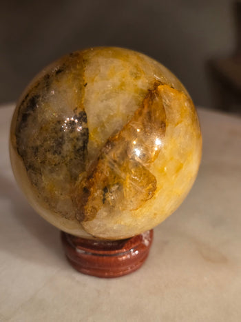 Golden healer quartz sphere with dark earthy inclusions and golden veils