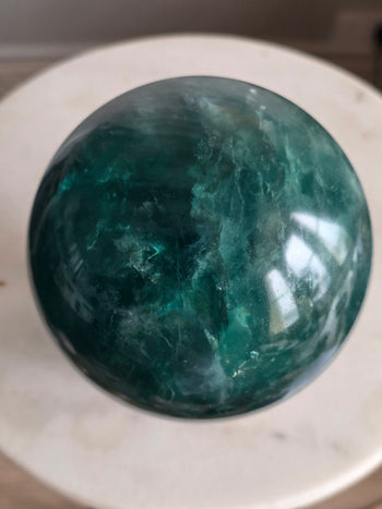 Top view of green fluorite crystal sphere showing emerald and teal colour zoning
