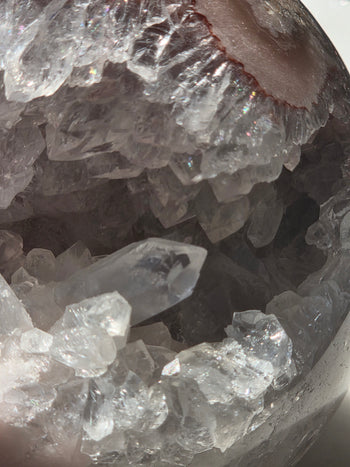 Close-up of crystal-lined cave opening in pink amethyst druzy sphere