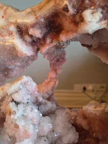 Pink crystal bridge across the window of a large pink amethyst geode